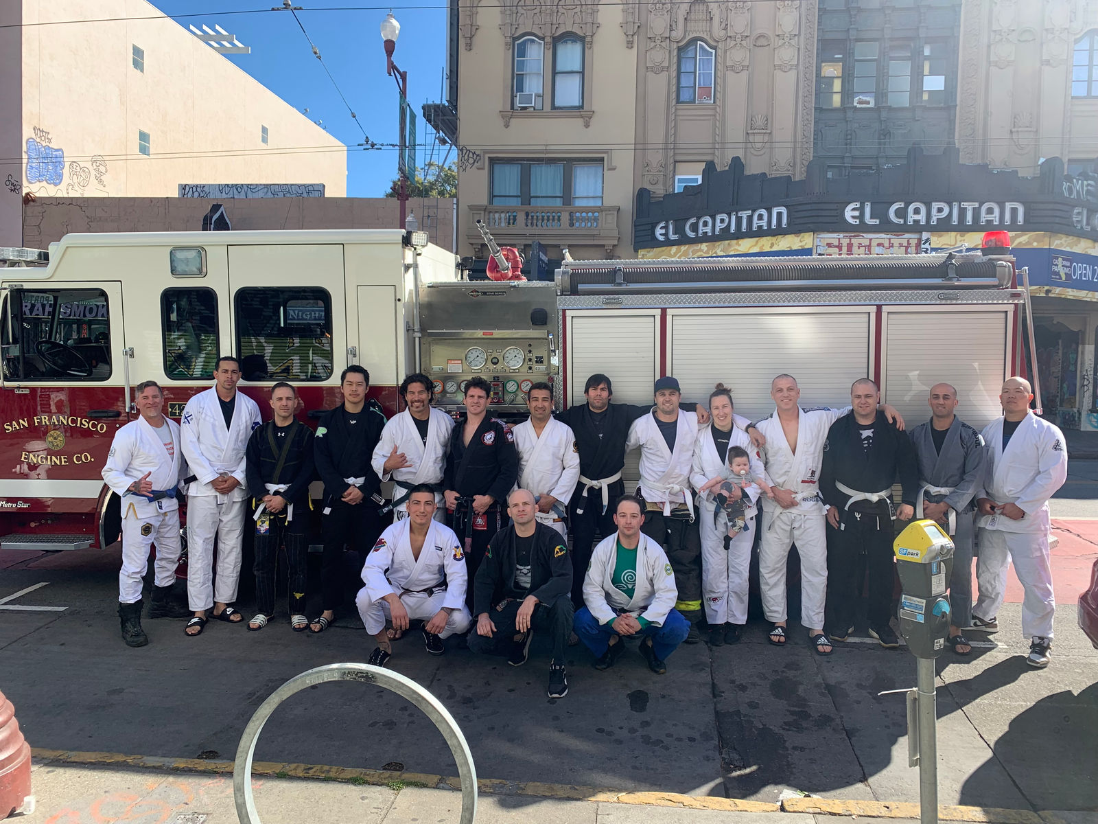 A large group photo in front of the rigs outside the El Capitan theatre