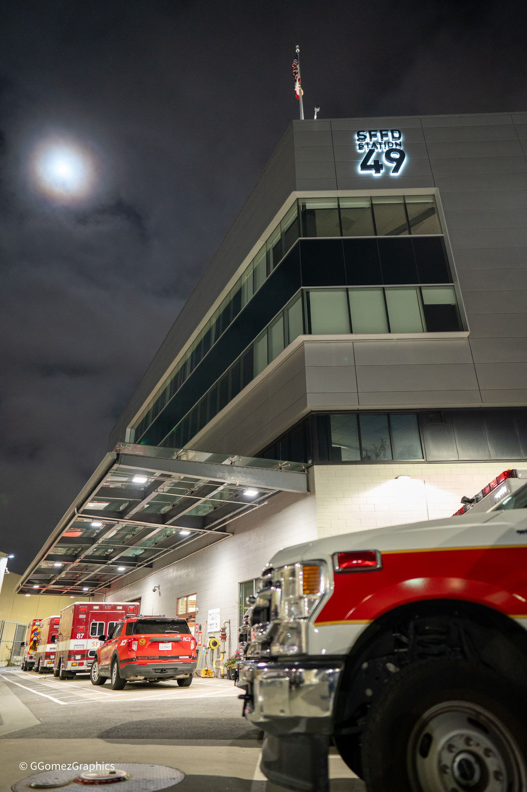 A firehouse lit up at night with the apparatus bay open