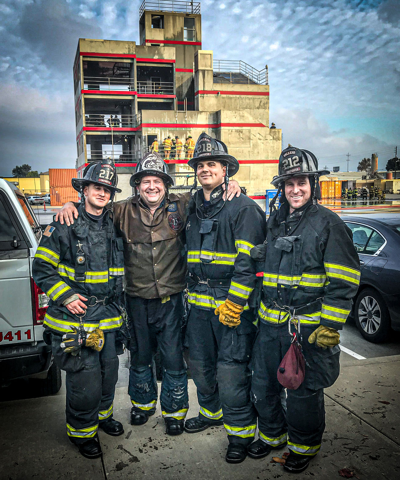 Four firefighters in turnouts outside a training tower